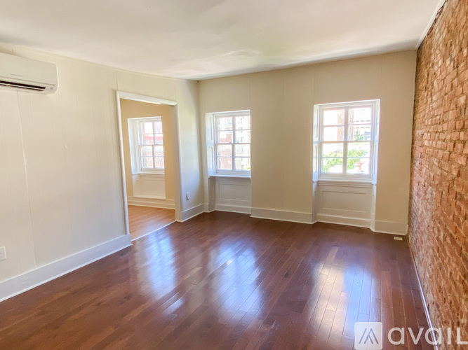 A room with wooden floors and three windows.