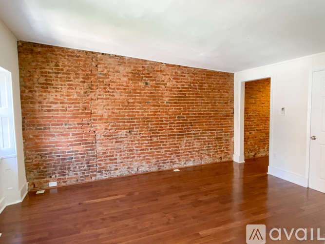 A room with a red brick wall and wooden flooring.