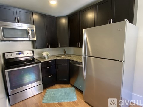 A kitchen with black cabinets and a stainless steel refrigerator.