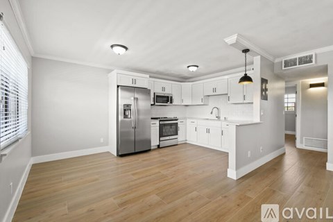 A kitchen with white cabinets and a wooden floor.