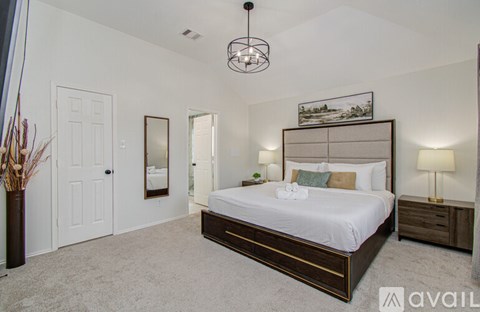 A bedroom with a large bed, a chandelier, and a mirror on the wall.