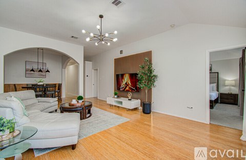 A living room with a white couch and a wooden floor.