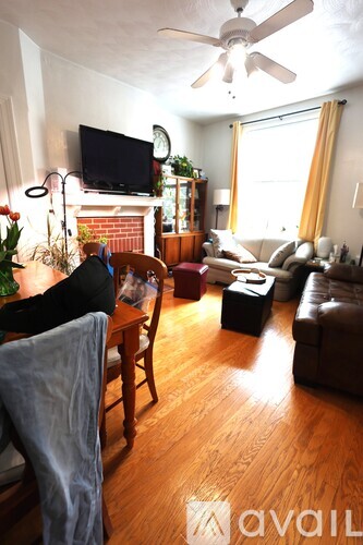 A living room with a television, a fireplace, and a wooden floor.