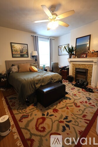 A bedroom with a bed, a fireplace, and a ceiling fan.