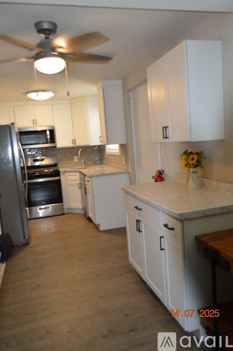 A kitchen with white cabinets and a wooden floor.
