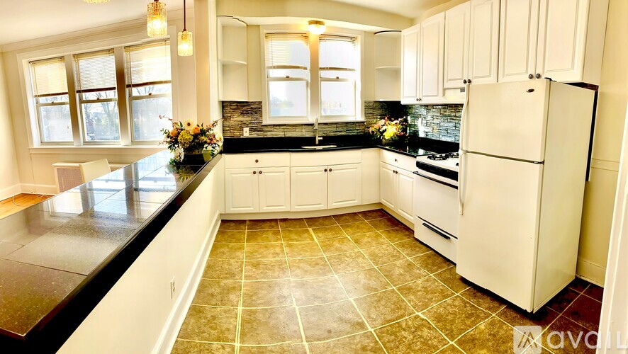 A kitchen with white appliances and a black countertop.