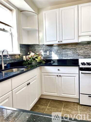 A kitchen with white cabinets and a black countertop.