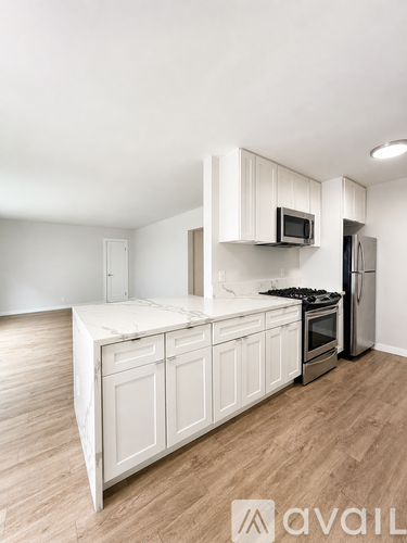 A kitchen with white cabinets and a wooden floor.