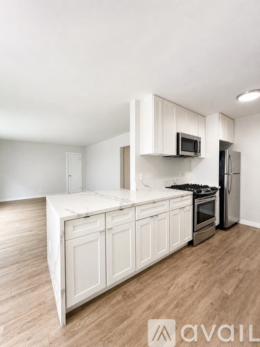 A kitchen with white cabinets and a wooden floor.