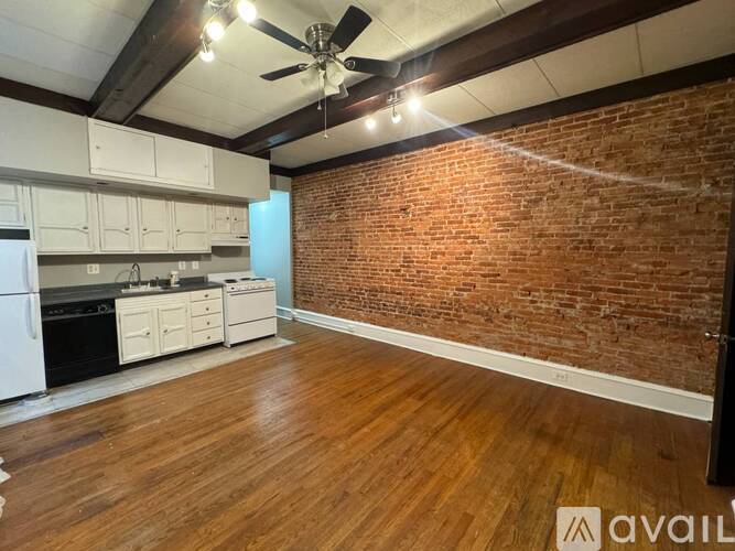 A room with wooden floors and a brick wall.