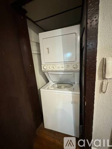 A small white washing machine is in a narrow space.
