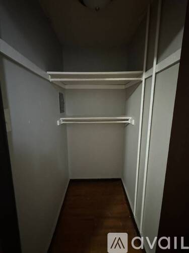 A small, empty room with a wooden floor and white walls.