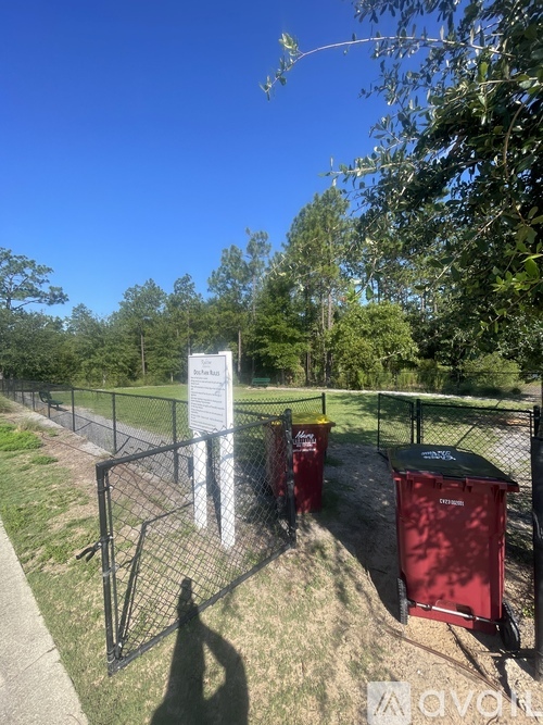 A sign is posted on a fence in front of a grassy area.
