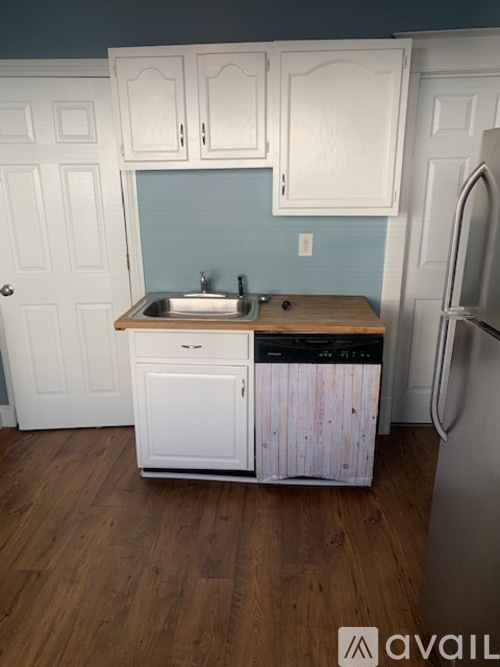 A kitchen with white cabinets and a wooden counter top.