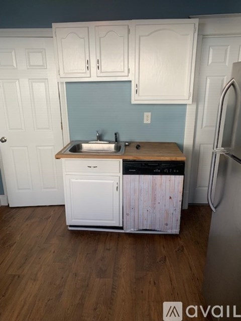 A kitchen with white cabinets and a wooden counter top.