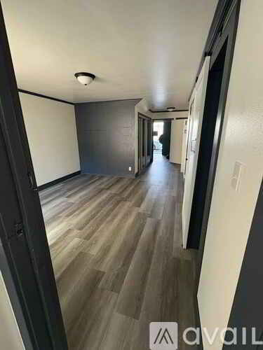 A long hallway with wood flooring and white walls.