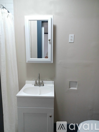 A white sink in a small bathroom with a mirror above it.