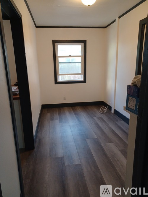 A room with a window and wooden flooring.