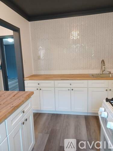 A kitchen with white cabinets and a wooden countertop.
