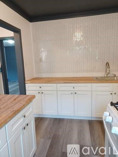 A kitchen with white cabinets and a wooden countertop.