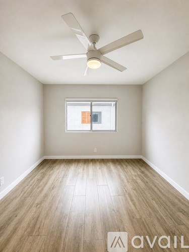 A room with a ceiling fan and wooden flooring.