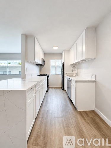A modern kitchen with white cabinets and a wooden floor.