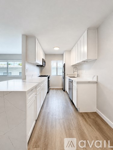 A modern kitchen with white cabinets and a wooden floor.