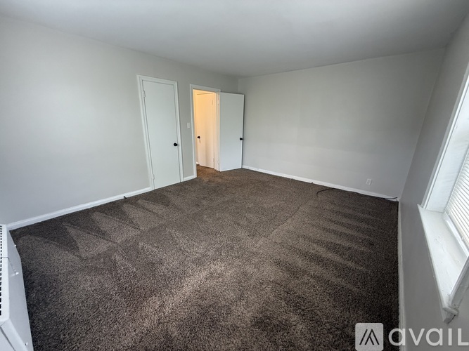 A carpeted room with a door and a window.