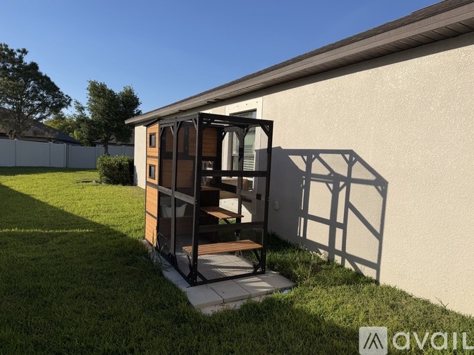 A small wooden structure with a glass door is situated in a grassy area.