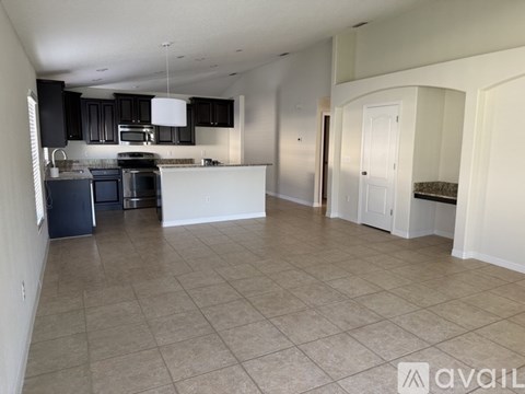 A spacious kitchen with black cabinets and a white island.
