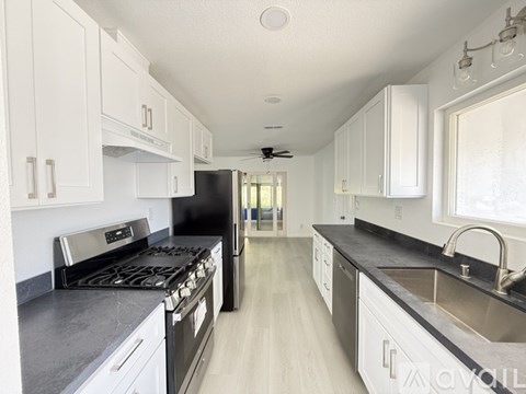 A kitchen with black appliances and white cabinets.