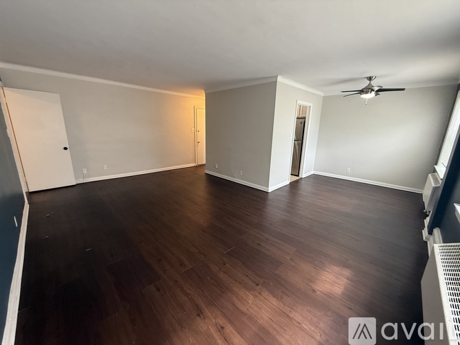 A spacious room with wooden flooring and a ceiling fan.