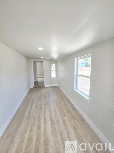 A long hallway with wood floors and white walls.