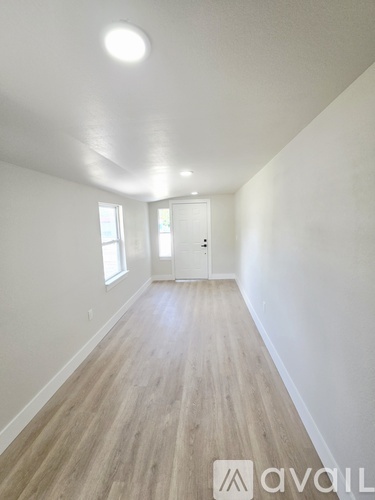 A long hallway with wood floors and white walls.