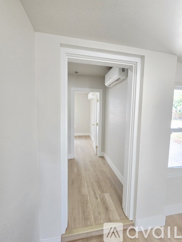 A hallway with a white door and a window on the right.