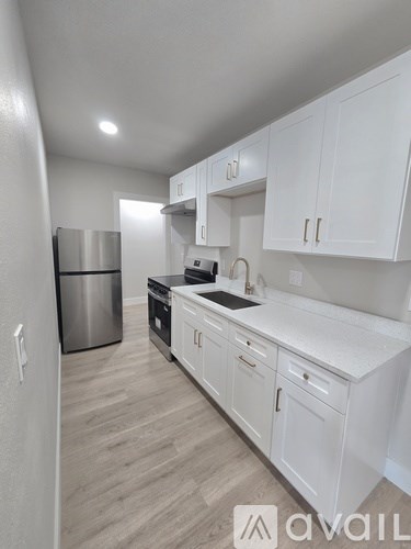 A kitchen with white cabinets and a stainless steel refrigerator.