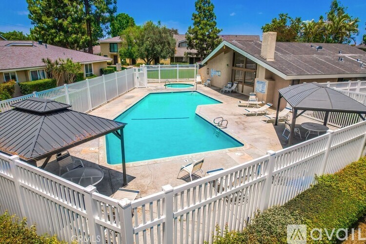 A pool surrounded by a white fence with a black umbrella.