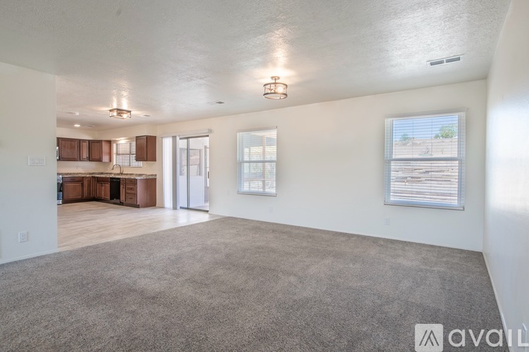 A spacious living room with a carpeted floor and a view of the outdoors through the window.