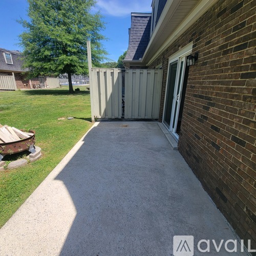 A concrete walkway leads to a white door in a brick building.