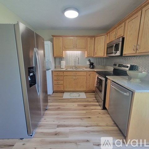 A kitchen with wooden cabinets and a stainless steel refrigerator.