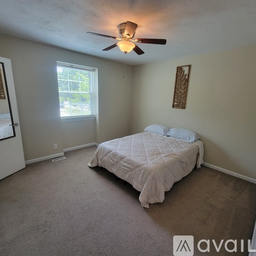 A bedroom with a bed, carpet, and a ceiling fan.