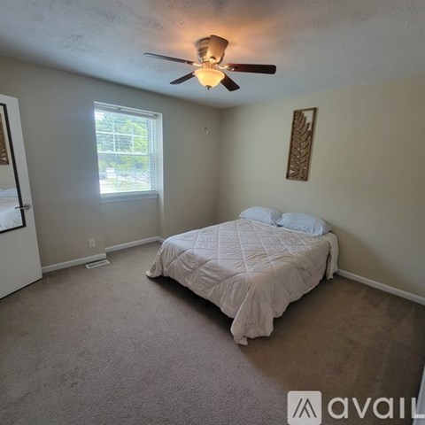 A bedroom with a bed, carpet, and a ceiling fan.
