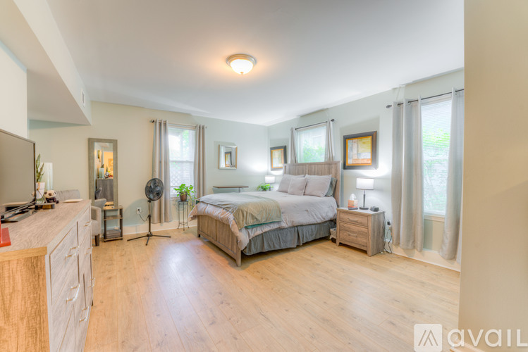 A bedroom with a large bed, a dresser, and a window with curtains.