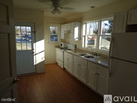 A kitchen with white cabinets and a fan on the ceiling.