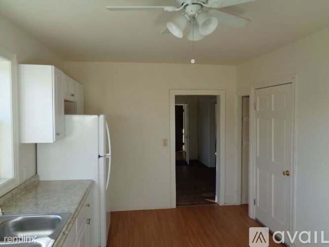 A kitchen with white appliances and a wooden floor.