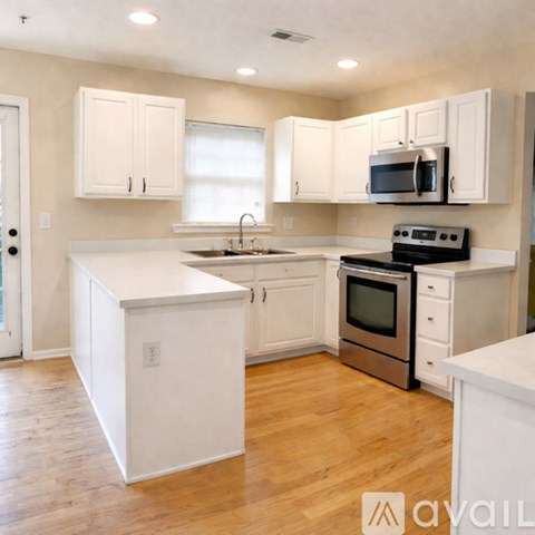 A kitchen with white cabinets and a wooden floor.