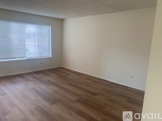 A room with wooden flooring and a window with blinds.