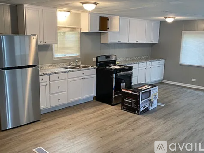 A kitchen with a stainless steel refrigerator, a black stove, and white cabinets.