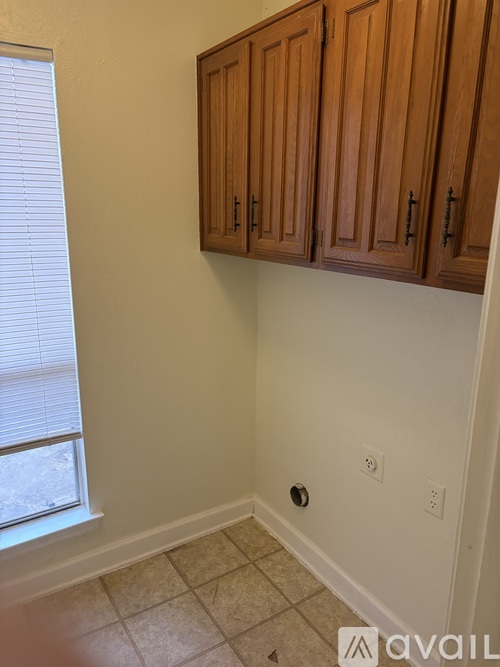 A kitchen with wooden cabinets and a window with blinds.