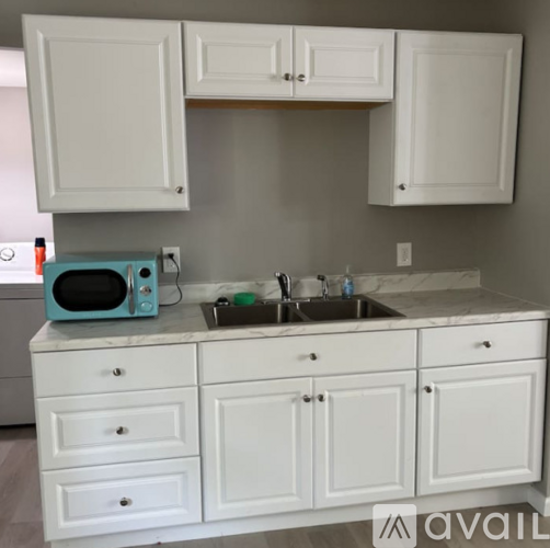 A kitchen with white cabinets and a blue toaster oven on the counter.